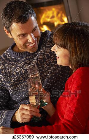 Middle Aged Couple Sitting Sofa By Cosy Log Fire With Glass Of Champagne View Large Photo Image Stock Photo - Middle Aged Couple Sitting Sofa By Cosy Log Fire With Glass Of Champagne. Fotosearch