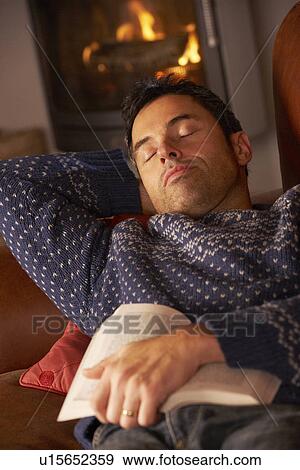 Stock Photo - Middle Aged Man Asleep With Book By Cosy Log Fire. Fotosearch
