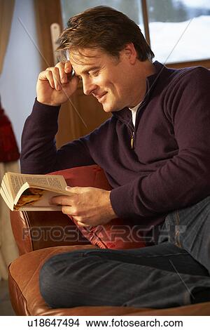Picture - Middle Aged Man Relaxing With Book Sitting On Sofa. Fotosearch