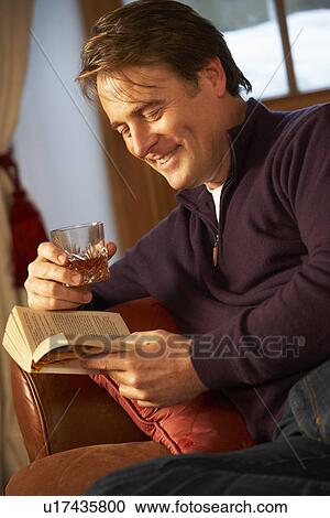 Middle Aged Man Relaxing With Book Sitting On Sofa Drinking Whisky View Large Photo Image Stock Image - Middle Aged Man Relaxing With Book Sitting On Sofa Drinking Whisky. Fotosearch