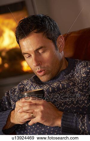 Middle Aged Man Relaxing With Hot Drink By Cosy Log Fire View Large Photo Image Stock Photo - Middle Aged Man Relaxing With Hot Drink By Cosy Log Fire. Fotosearch
