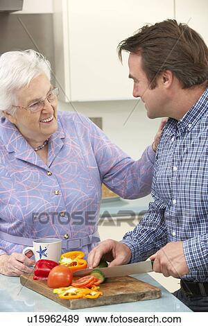 Stock Photo - Mother and adult son preparing meal together. Fotosearch
