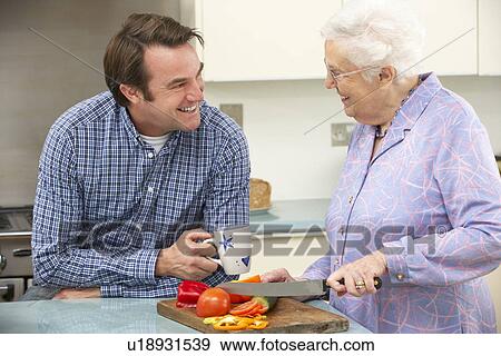 Stock Photo - Mother and adult son preparing meal together. Fotosearch