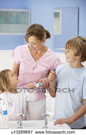 Stock Photo - Mother and children cleaning teeth in bathroom. Fotosearch