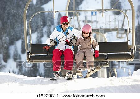 Stock Image - Mother And Daughter Getting Off chair Lift On Ski Holiday In Mountains. Fotosearch