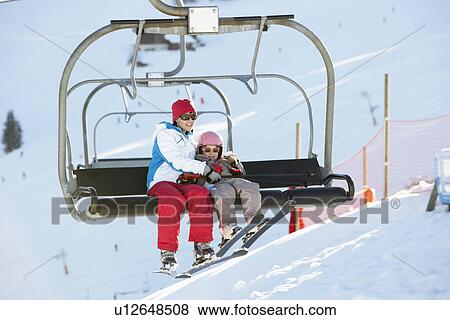 Stock Photo - Mother And Daughter Getting Off chair Lift On Ski Holiday In Mountains. Fotosearch