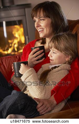 Mother And Daughter Relaxing With Hot Drink Watching TV By Cosy Log Fire View Large Photo Image Stock Photography - Mother And Daughter Relaxing With Hot Drink Watching TV By Cosy Log Fire. Fotosearch
