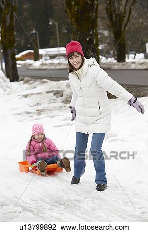 Mother Pulling Daughter On Sledge Along Snowy Street In Ski Resort View Large Photo Image Stock Image - Mother Pulling Daughter On Sledge Along Snowy Street In Ski Resort. Fotosearch