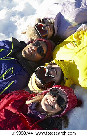 Picture - Overhead View Of Teenage Family Lying In Snow On Ski Holiday In Mountains. Fotosearch