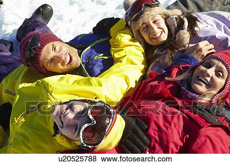 Stock Photo - Overhead View Of Teenage Family Lying In Snow On Ski Holiday In Mountains. Fotosearch
