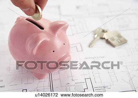 Stock Image - Piggybank with house plans and keys. Fotosearch