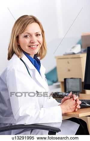 Stock Photography - Portrait American doctor sitting at desk. Fotosearch