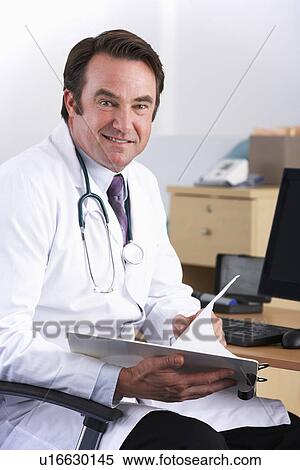 Stock Photography - Portrait American doctor sitting at desk. Fotosearch