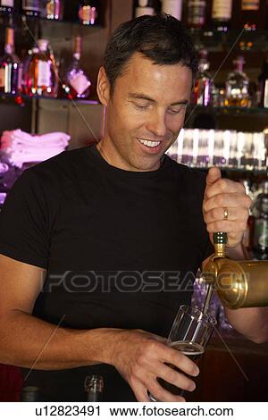 Portrait Of Barman Standing Behind Bar Pouring Beer View Large Photo Image Stock Image - Portrait Of Barman Standing Behind Bar Pouring Beer. Fotosearch