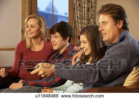 Stock Photo - Portrait Of Family Relaxing On Sofa Together Watching TV. Fotosearch