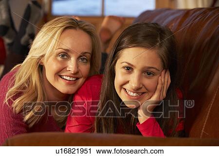 Stock Image - Portrait Of Mother And Daughter Relaxing On Sofa Together. Fotosearch