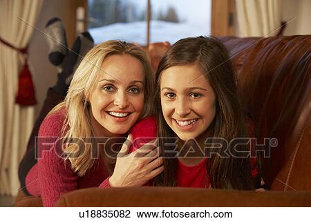 Stock Image - Portrait Of Mother And Daughter Relaxing On Sofa Together. Fotosearch