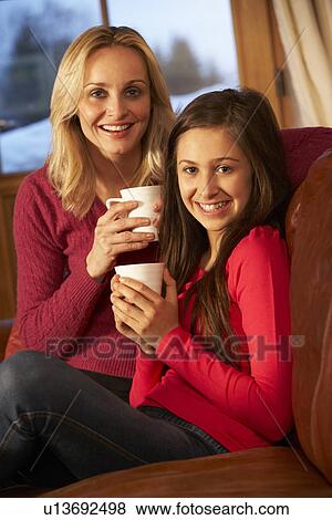 Stock Photo - Portrait Of Mother And Daughter Relaxing On Sofa Together With Hot Drink. Fotosearch