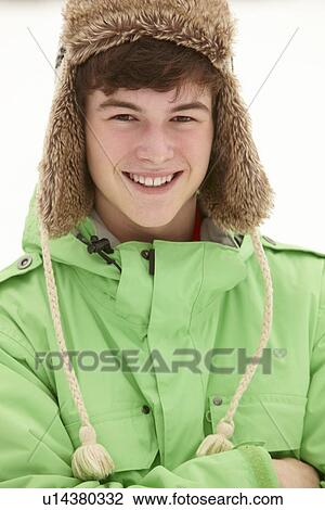 Stock Image - Portrait Of Teenage Boy In Snow Wearing Fur Hat. Fotosearch