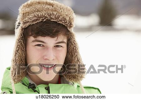 Stock Image - Portrait Of Teenage Boy In Snow Wearing Fur Hat. Fotosearch