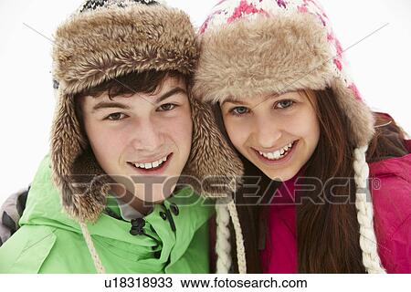 Stock Image - Portrait Of Teenage Couple In Snow Wearing Fur Hats. Fotosearch