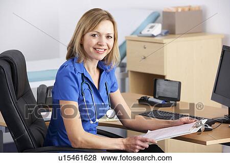 Stock Photo - Portrait UK doctor sitting at desk. Fotosearch