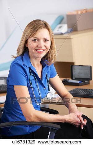 Stock Photo - Portrait UK doctor sitting at desk. Fotosearch