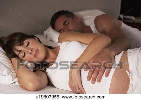Stock Photograph - Pregnant woman and husband in bed. Fotosearch