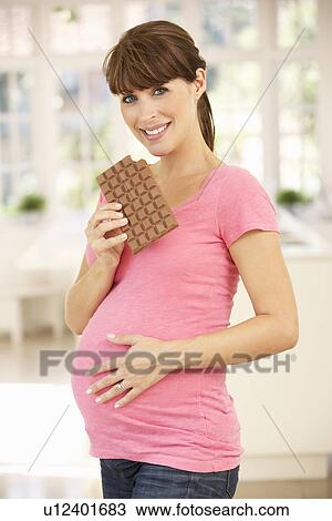 Stock Image - Pregnant woman eating chocolate. Fotosearch