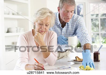 Stock Image - Retired man clearing up after breakfast. Fotosearch