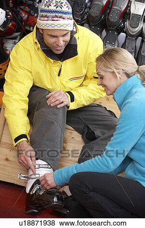 Stock Photo - Sales Assistant Helping Man To Try On Ski Boots In Hire Shop. Fotosearch