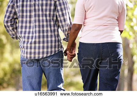 Stock Image - Senior couple walking in park. Fotosearch
