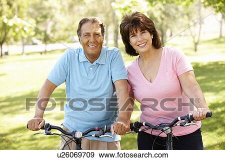 Stock Photo - Senior Hispanic couple on bikes. Fotosearch