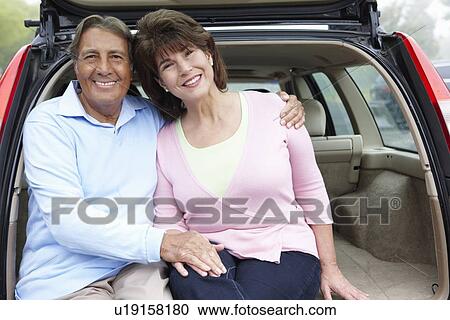 Stock Image - Senior Hispanic couple outdoors with car. Fotosearch