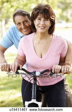 Stock Image - Senior Hispanic couple with bike. Fotosearch