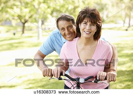 Stock Image - Senior Hispanic couple with bike. Fotosearch