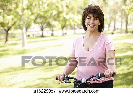 Stock Photo - Senior Hispanic woman with bike. Fotosearch