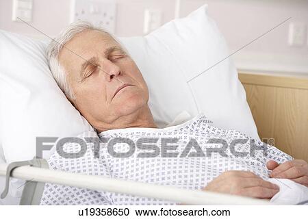 Stock Image - Senior man asleep in hospital bed. Fotosearch