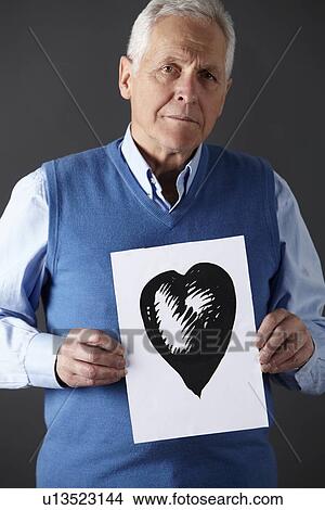 Picture - Senior man holding ink drawing of heart. Fotosearch