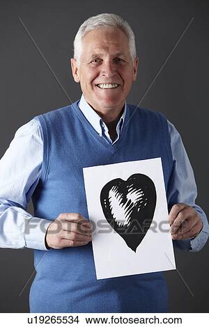 Picture - Senior man holding ink drawing of heart. Fotosearch