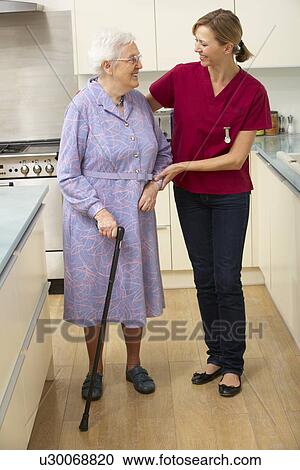 Stock Image - Senior woman and carer in kitchen. Fotosearch