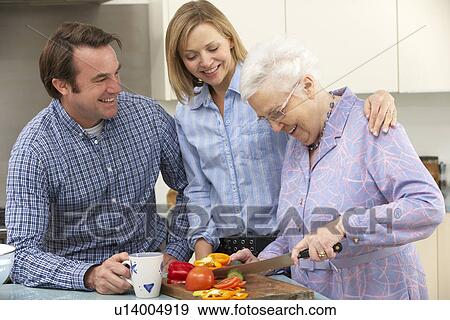 Stock Photo - Senior woman and family preparing meal together. Fotosearch