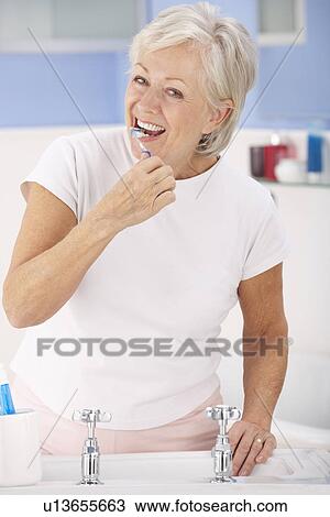 Stock Image - Senior woman brushing teeth. Fotosearch