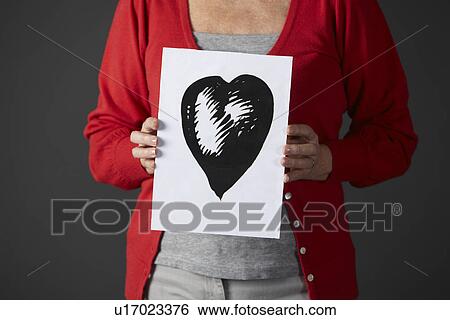 Stock Photograph - Senior woman holding ink drawing of heart. Fotosearch