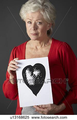 Stock Photography - Senior woman holding ink drawing of heart. Fotosearch