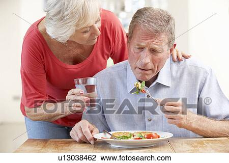 Stock Image - Senior woman looking after sick husband. Fotosearch