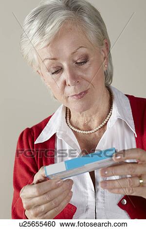 Stock Image - Senior woman looking at prescription drug pack. Fotosearch