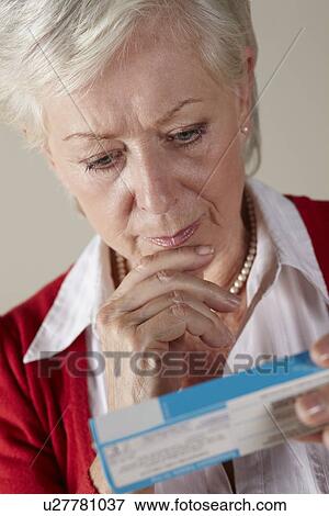 Stock Photo - Senior woman looking at prescription drug pack. Fotosearch