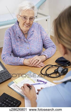 Stock Image - Senior woman patient with UK nurse. Fotosearch