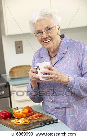 Stock Photo - Senior woman preparing food in domestic kitchen. Fotosearch
